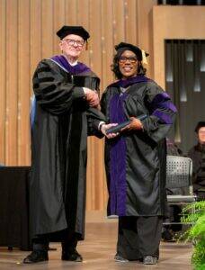 JD Student in Regalia receiving Diploma Tube from Dean Halvorson