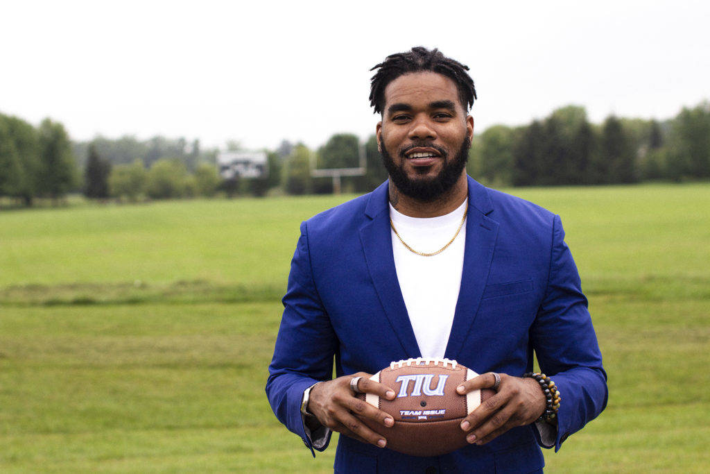 Quintin Demps holding a football in front of the Trojan football field