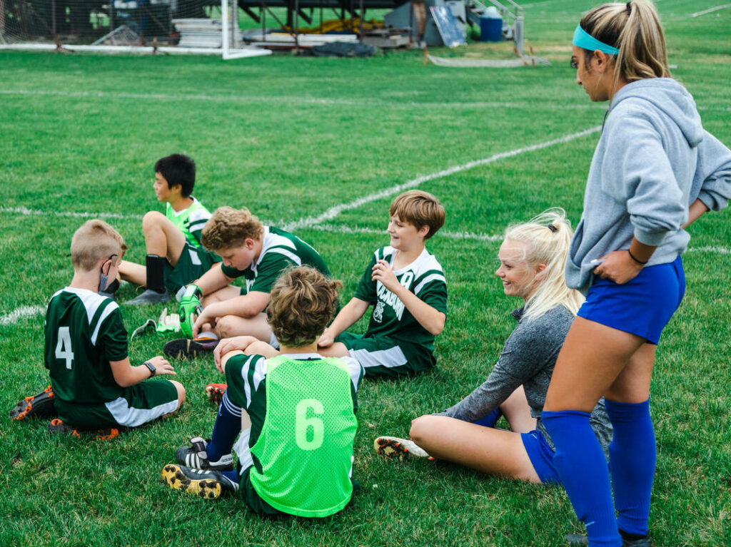 TIU Soccer laughing with middle schoolers on the field