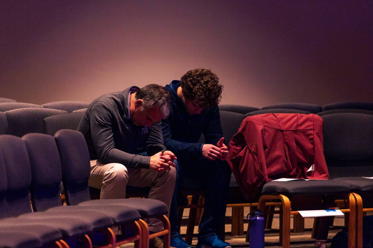 President Perrin prays with undergraduate student