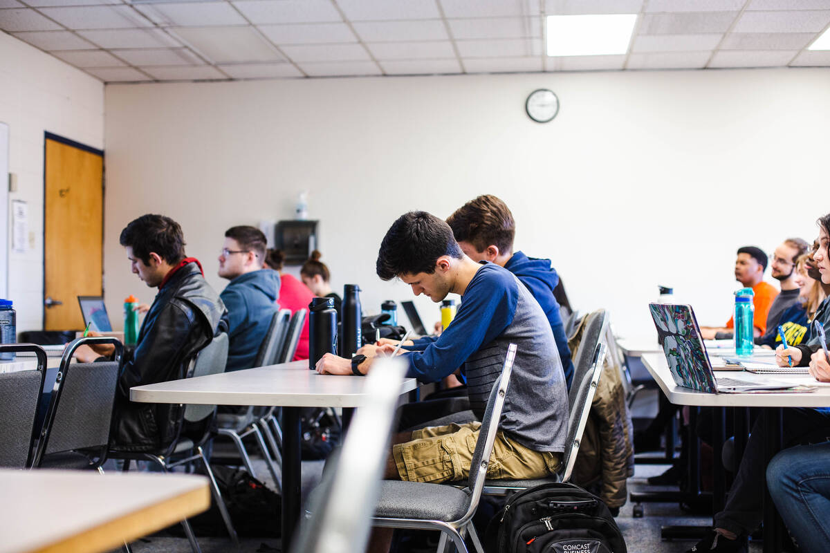 Trinity College students in a classroom taking notes and listening to their professor. 