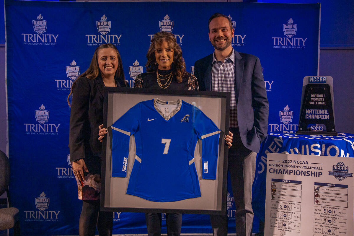 Alumna Renee Lois with Coaches Luke Ward and Kennedy Mang, holding her #7 jersey. 